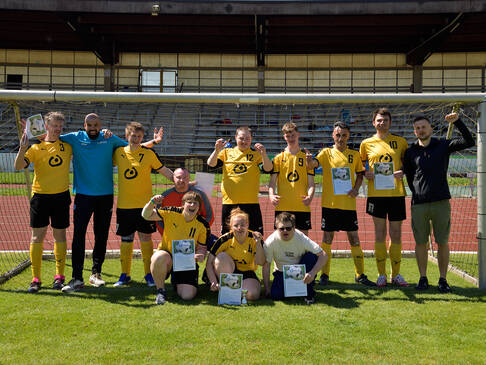 Ein Team mit gelben Trikots steht im Tor.