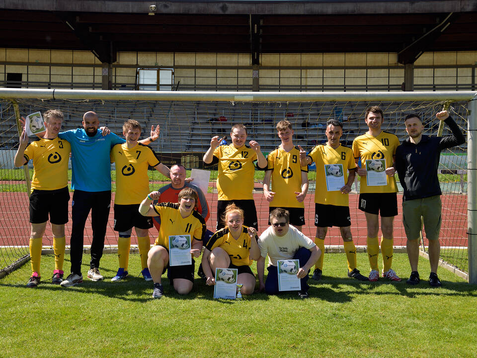 Ein Team mit gelben Trikots steht im Tor.