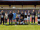 Ein Team mit schwarzen Trikots steht im Tor.