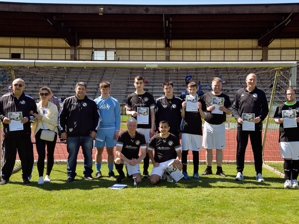Ein Team mit schwarzen Trikots steht im Tor.