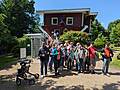 Gruppenfoto vor einem Haus welches auf dem Dach steht.