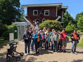 Gruppenfoto vor einem Haus welches auf dem Dach steht.