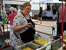 Eine Frau steht an der Fritteuse und macht Pommes.