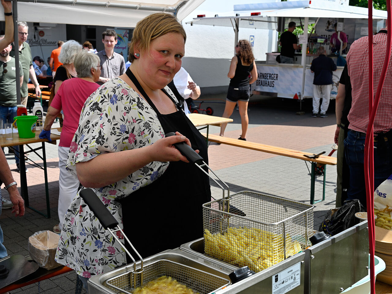 Eine Frau steht an der Fritteuse und macht Pommes.
