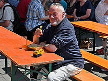 Ein MAnn sitzt am Tisch und isst Pommes.