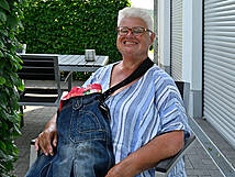 Eine Person sitzt im Schatten auf einem STuhl und lacht.