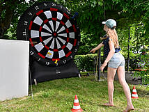 Ein Mädchen wirft auf eine riesengroße Dartscheibe.