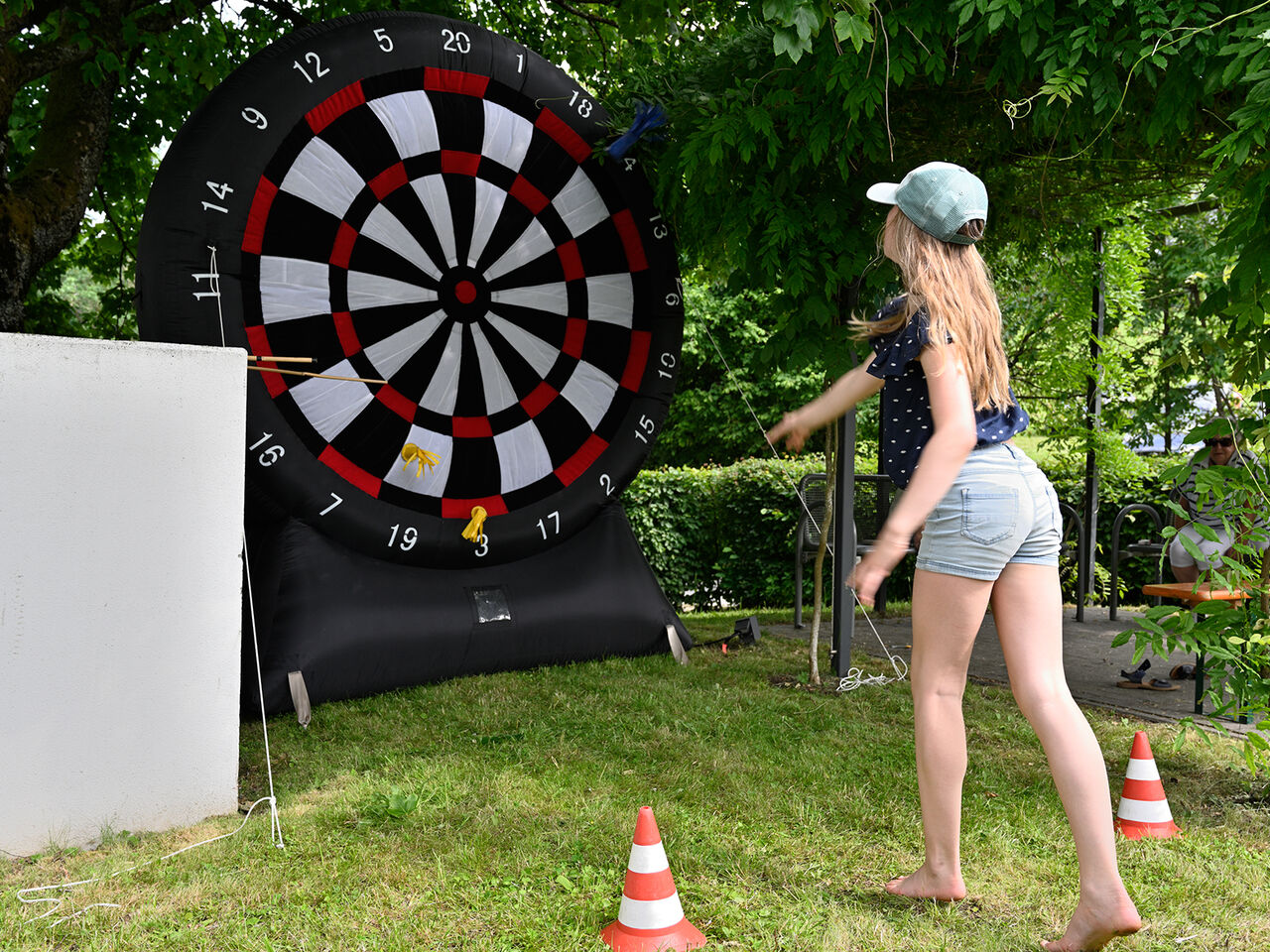 Ein Mädchen wirft auf eine riesengroße Dartscheibe.