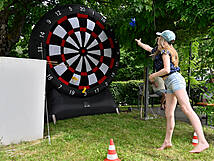 Ein Mädchen wirft auf eine riesengroße Dartscheibe.