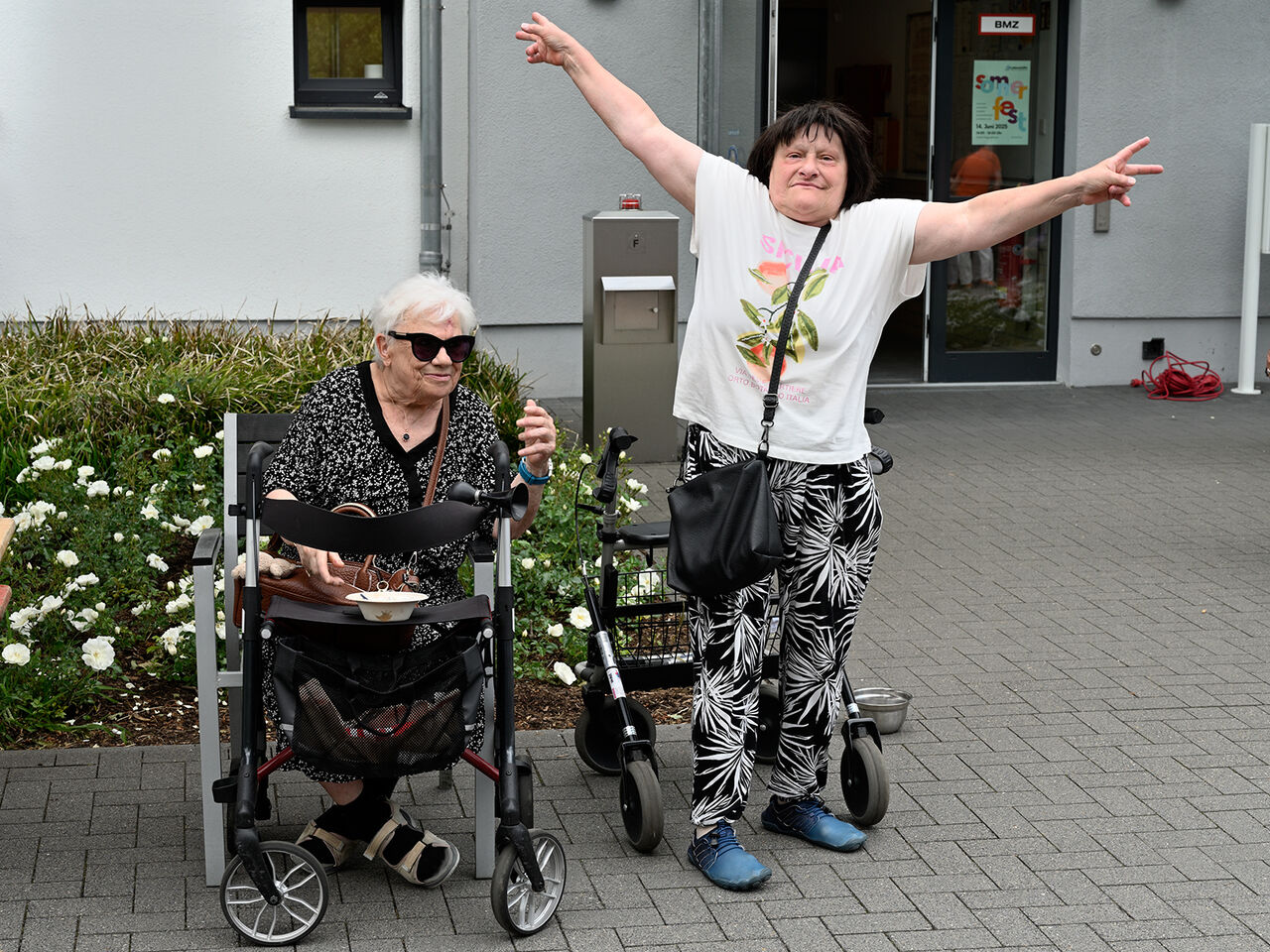 Zwei gut gelaunte Frauen vor einem Gebäude.