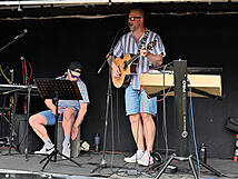 Zwei Personen auf der Bühne, einer mit einer Gitarre und der andere mit einem Cachon.