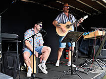 Zwei Personen auf der Bühne, einer mit einer Gitarre und der andere mit einem Cachon.