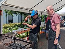 Zwei Männer stehen am Grill.