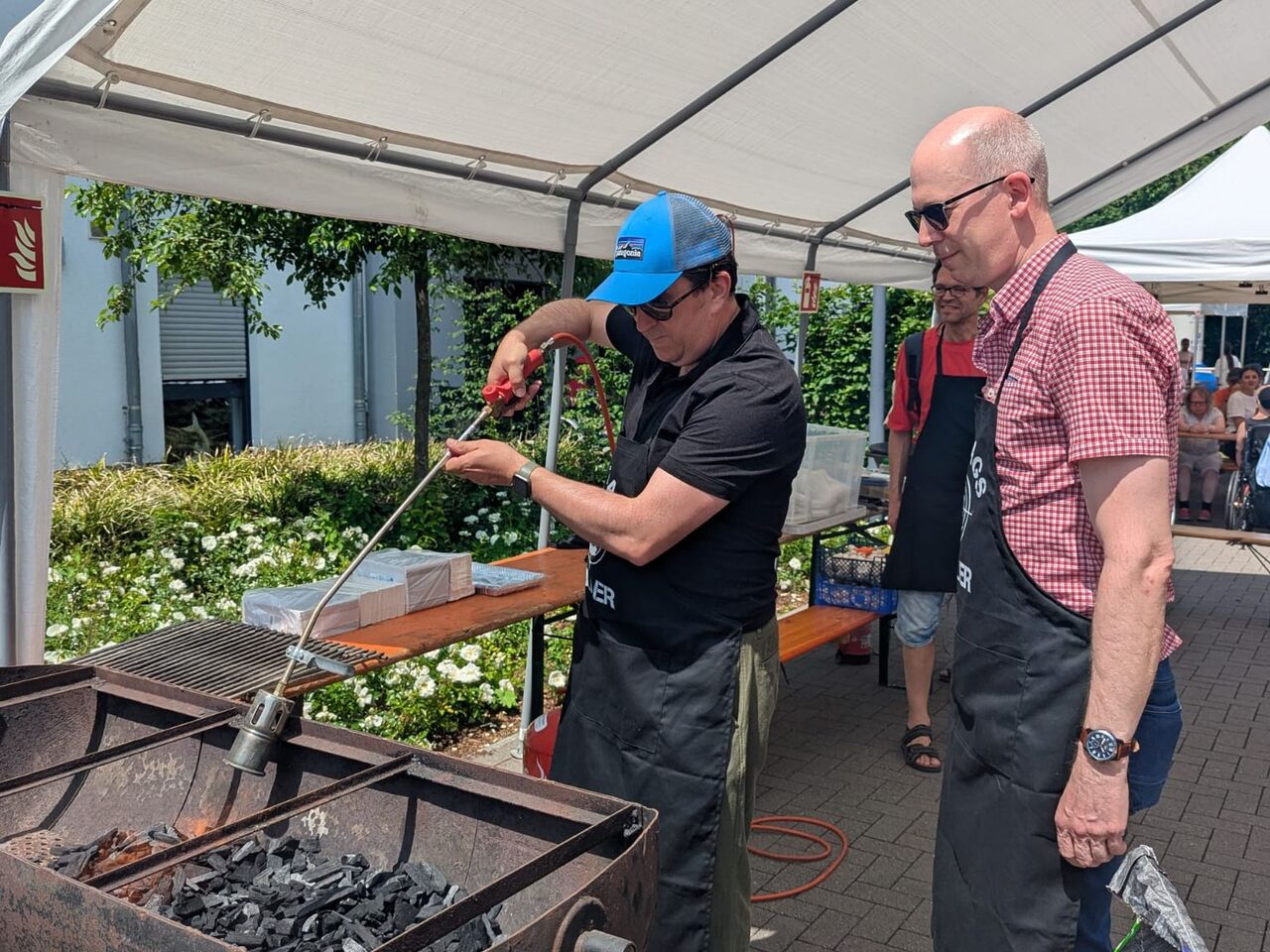 Zwei Männer stehen am Grill.