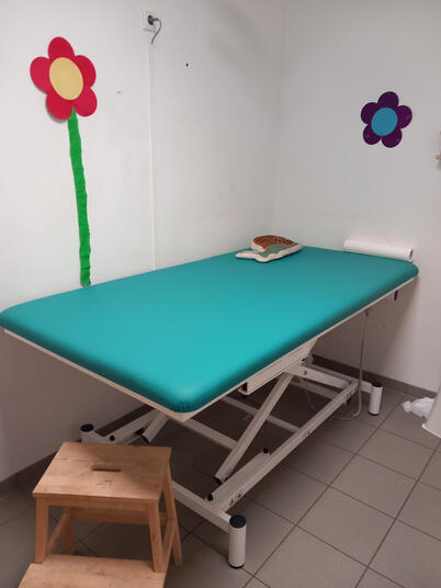 Eine Therapieliege mit türkiser Liegefläche.