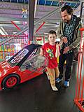 Ein Kind steigt aus einem roten Kinderauto.