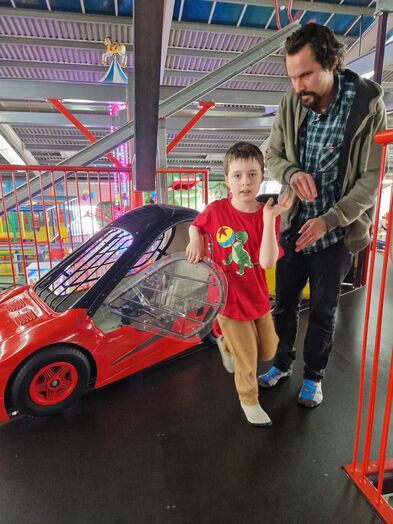Ein Kind steigt aus einem roten Kinderauto.