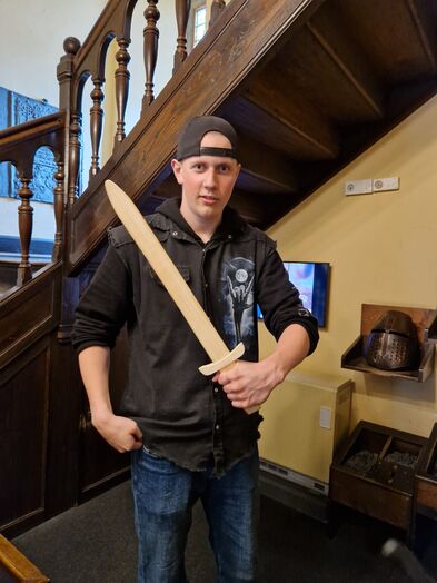 Ein Jugendlicher mit einem Holzschwert in der Hand.