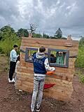 Mehrere Kinder stehen vor und hinter einer Fotowand aus Holz.