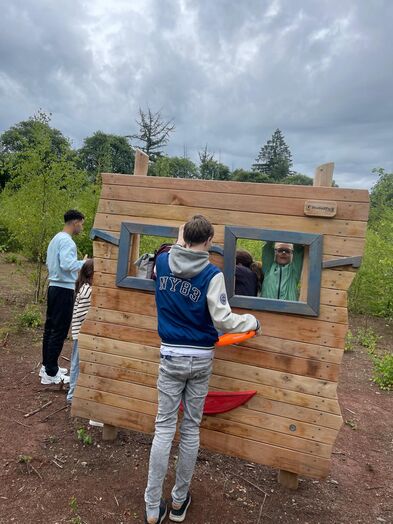 Mehrere Kinder stehen vor und hinter einer Fotowand aus Holz.