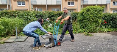 Ein schwerer Stein wird auf eine Sackkarre gehoben