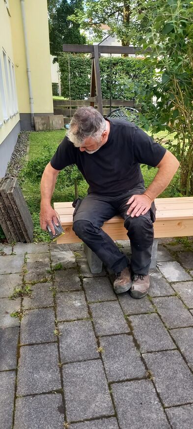 Ein Handwerker schleift das Holz ab.