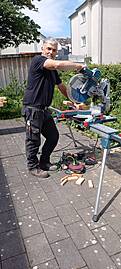 Ein Handwerker schneidet Haolzbalken an einer Kreissäge.