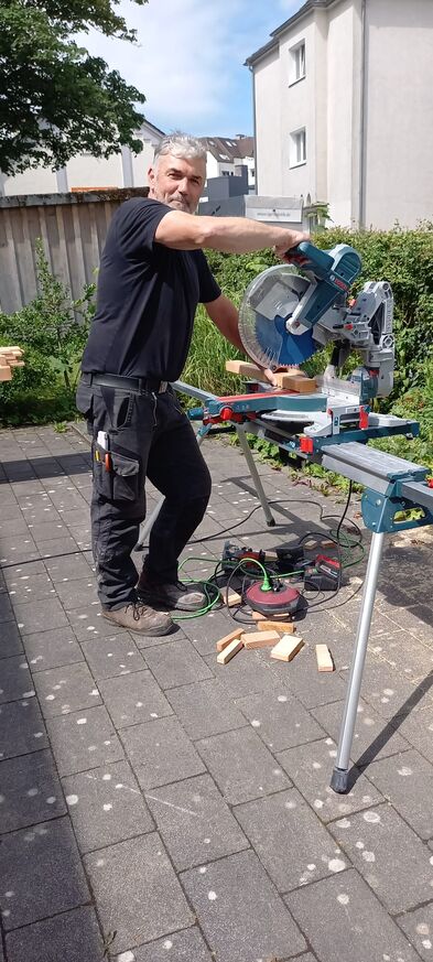 Ein Handwerker schneidet Haolzbalken an einer Kreissäge.