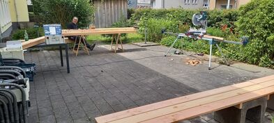 Ein Handwerker sitzt hinter Holzbalken
