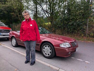 Eine Person neben einem Oldtimer.