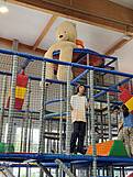Ein Indoorkletterpark und oben drauf sitzt ein sehr großer Teddybär.