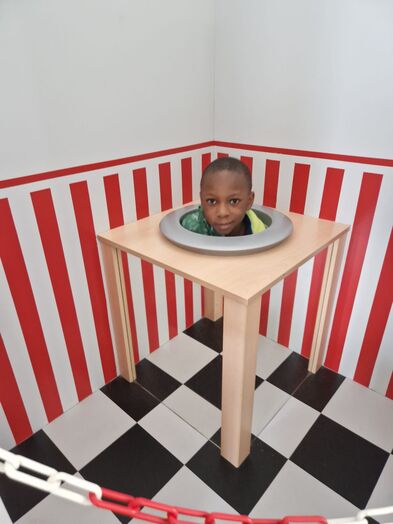 Ein Junge sitzt in einer Spiegelbox.