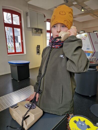 Ein Junge hält den Telefonhörer eines analogen Telefons in der Hand.