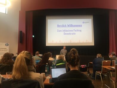 Auf einer großen Leinwand steht herzlich Willkommen zum Fachtag