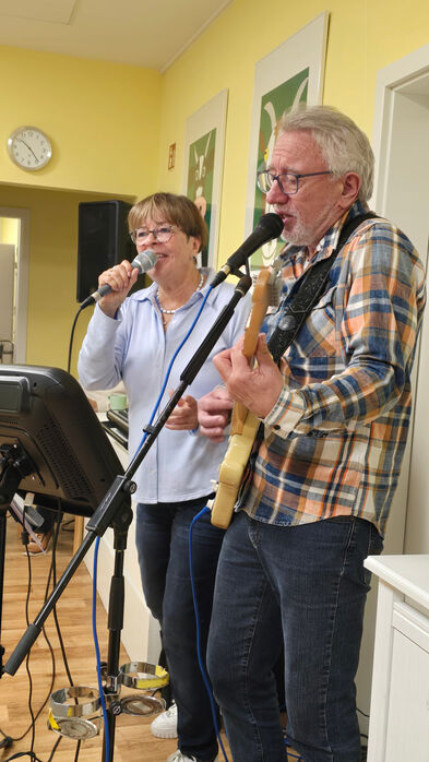 Ein Mann spielt Gitarre und singt, eine Frau singt mit.