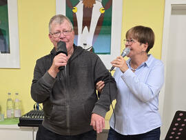 Ein Mann und eine Frau mit  Mikrofonen in der Hand.