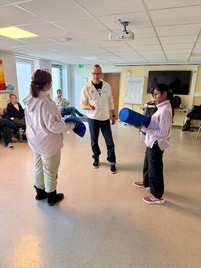 Zwei Personen stehen sich gegenüber und ein Mann steht daneben.