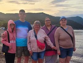 Gruppenfoto am Strand bei Sonnenuntergang.