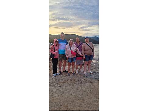 Gruppenfoto am Strand bei Sonnenuntergang.
