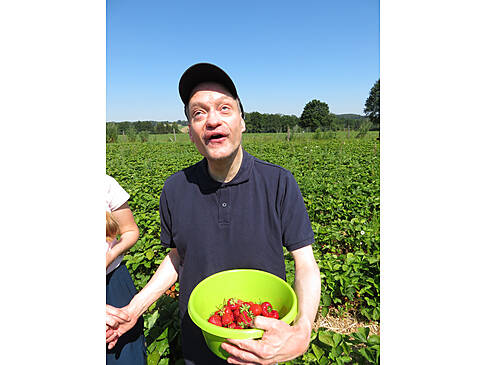 Ein Kunde im Erdbeerfeld mit einer Schüssel Erdbeeren.