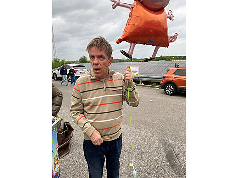 Ein Mann hält einen schwebenden Ballon in der Hand.