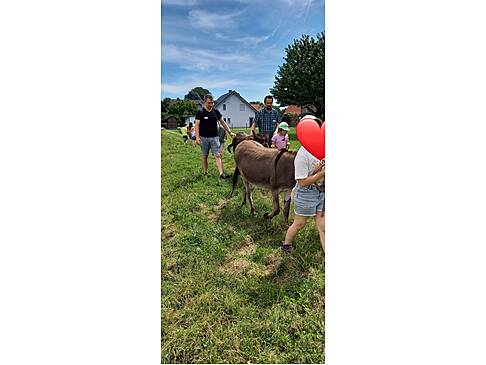 Kinde und zwei Männer haben Tiere an der Leine.