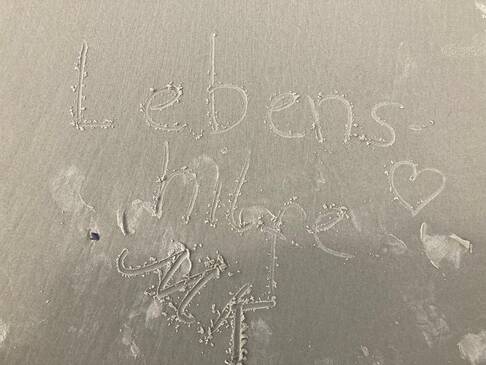 Lebenshilfe MK steht im Sand.