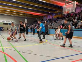 Frauen und Männer mit und ohne Hilfsmittel spielen zusammen Basketball