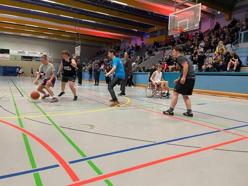 Frauen und Männer mit und ohne Hilfsmittel spielen zusammen Basketball