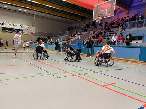 Frauen und Männer mit und ohne Hilfsmittel spielen zusammen Basketball