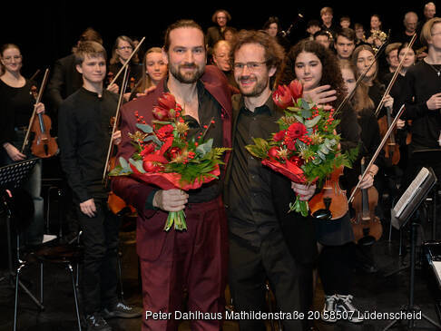 Zwei Herren mit Blumensträßen vor dem Orchester.
