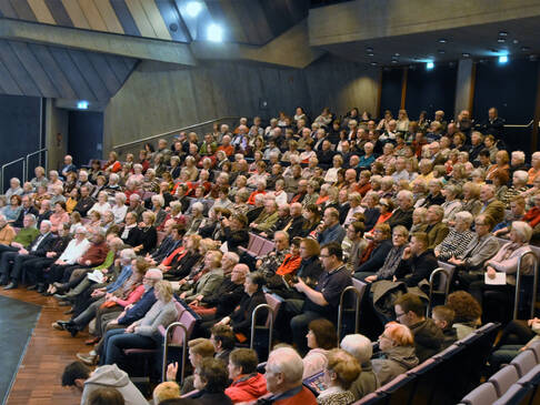 Viele Menschen sitzen in einem Saal.