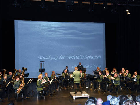 Musiker eines Schützenvereins spielen auf einer Bühne auf ihren Instrumenten.