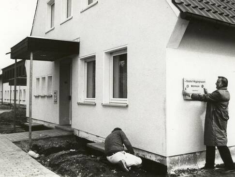 Ein Schild wird am Gebäude angebracht.